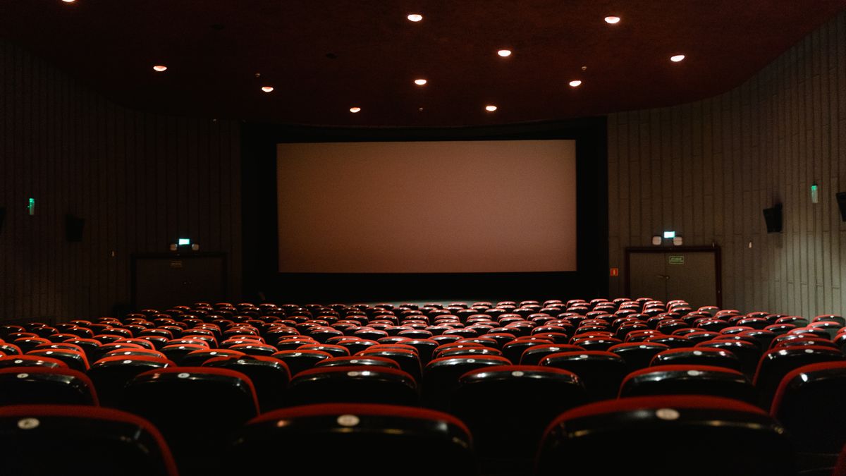 Ruang bioskop dengan deretan kursi merah menghadap layar